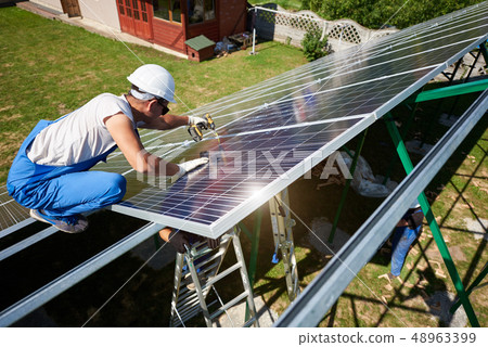 Professional worker installing solar panels on the green metal construction 48963399
