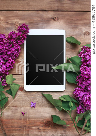 Bouquet of lilac flowers on wooden table with tablet. Top view Bouquet of lilac flowers on wooden table with tablet. Top view 48963794
