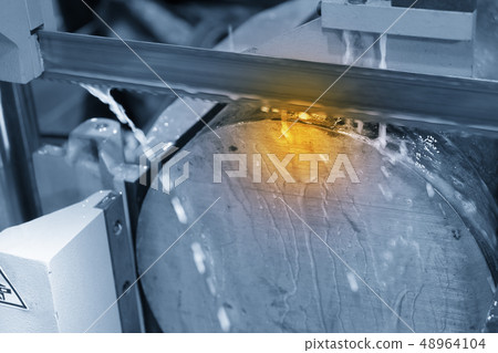 The band saw machine cutting raw metals . The band saw machine cutting raw metals . 48964104