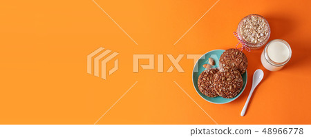 Oatmeal cookies with nuts on a plate, cup of milk 48966778