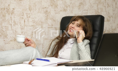 woman in office drinking coffee resting in workplace. beautiful businesswoman with phone sits in a woman in office drinking coffee resting in workplace. beautiful businesswoman with phone sits in a 48966921