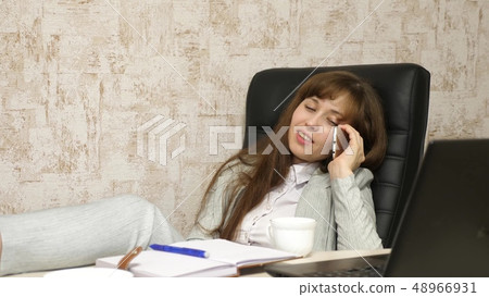 woman in office drinking coffee resting in workplace. beautiful businesswoman with phone sits in a 48966931