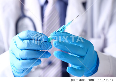 Physician arms wearing protective blue gloves prepare syringe 48967075