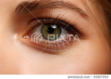 Female left emerald green coloured eye extreme closeup 48967094