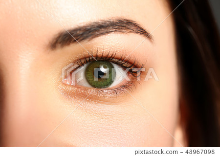 Female left emerald green coloured eye extreme closeup 48967098