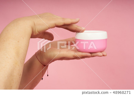 Senior woman hands applying cream on hands on coral background Senior woman hands applying cream on hands on coral background 48968271