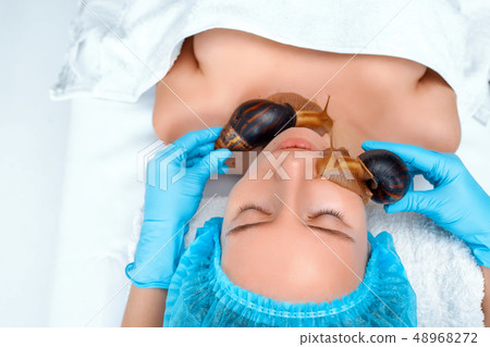 Young woman undergoing treatment with giant Achatina snails in beauty salon Young woman undergoing treatment with giant Achatina snails in beauty salon 48968272