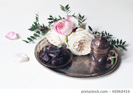Ramadan Kareem greeting card, invitation. Plate with dates fruit, bronze coffee cup, pink roses and 48968458
