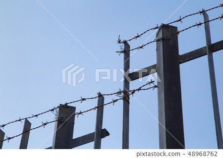 Iron fence and barbed wire 48968762