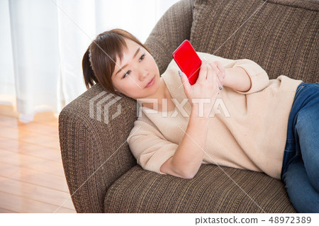 A woman who uses a smartphone on a couch 48972389