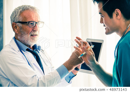 Doctors working with tablet computer at hospital. Doctors working with tablet computer at hospital. 48973143