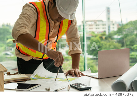 Young man architect or engineer working at desk. Young man architect or engineer working at desk. 48973372