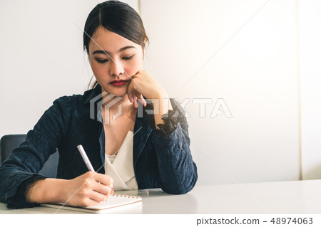 Beautiful young Asian woman writes on notebook. Beautiful young Asian woman writes on notebook. 48974063