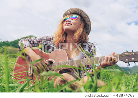 Happy woman plays guitar with nature background. 48974762