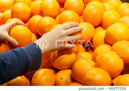 A housewife's hand picking oranges from a large mart fruit corner 48975526