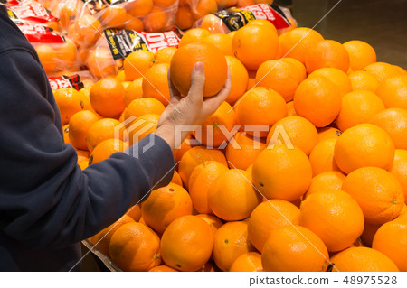 A housewife's hand picking oranges from a large mart fruit corner 48975528