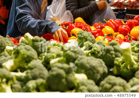 A hand picking vegetables (paprika, broccoli) at a large mart vegetable corner A hand picking vegetables (paprika, broccoli) at a large mart vegetable corner 48975549