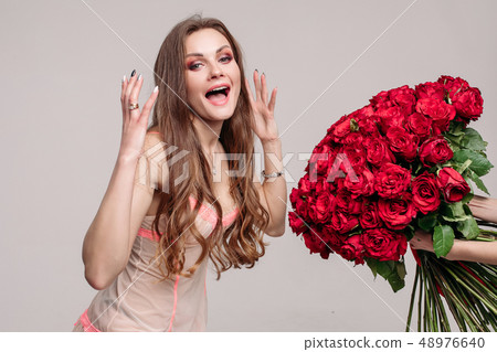 Gorgeous brunette woman in night gown smelling red Gorgeous brunette woman in night gown smelling red 48976640