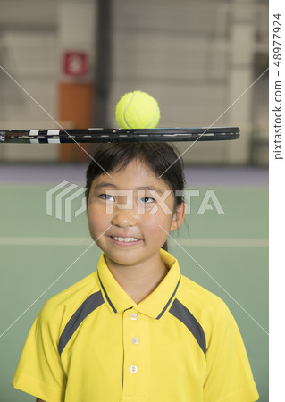 Kids tennis school image Children carrying a racket and tennis ball on their head 48977924
