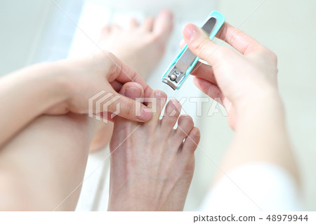 A woman cutting a nail of a foot A woman cutting a nail of a foot 48979944