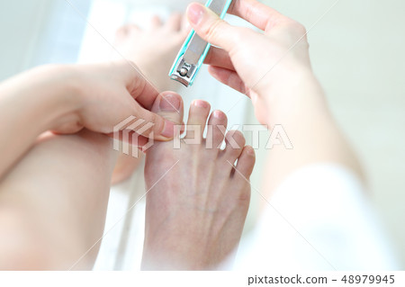 A woman cutting a nail of a foot A woman cutting a nail of a foot 48979945