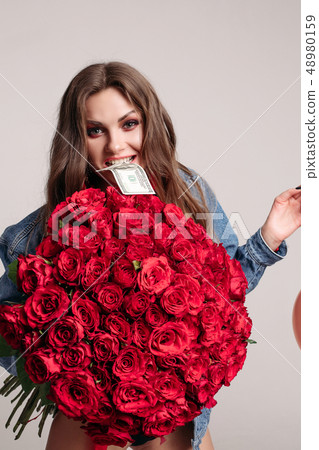 Cheeky woman keeping bouquet and biting banknote 48980159