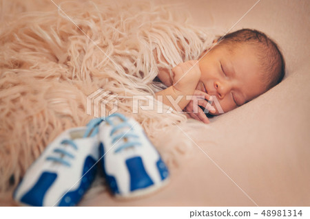 Newborn baby and a pair of baby shoes 48981314