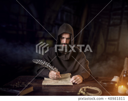 Medieval monk in robe writes with a goose feather Medieval monk in robe writes with a goose feather 48981811