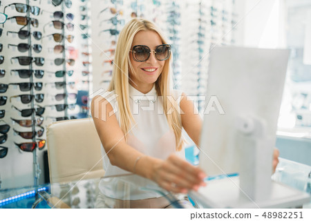 Female customer in sunglasses looks at the mirror Female customer in sunglasses looks at the mirror 48982251
