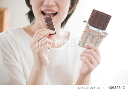 吃巧克力的年輕日本婦女的手 吃巧克力的年輕日本婦女的手 48982842