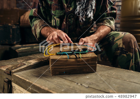 Terrorist in uniform sets bomb on the barrels Terrorist in uniform sets bomb on the barrels 48982947