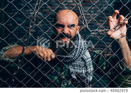 Violent terrorist with knife against metal grid 48982978