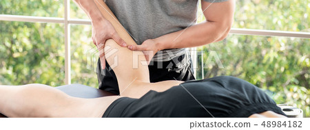 Male therapist giving leg massage to athlete Male therapist giving leg massage to athlete 48984182