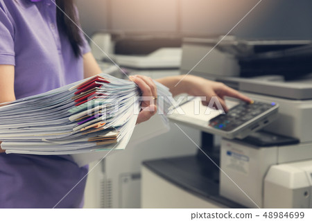 Bussinesswoman using copier machine to copy heap 48984699