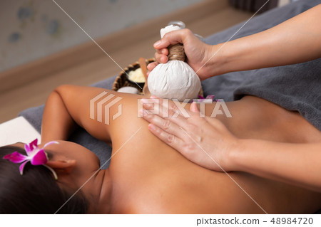 Asian woman enjoying a salt scrub massage at spa. Asian woman enjoying a salt scrub massage at spa. 48984720