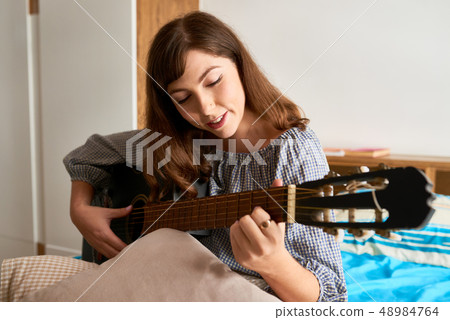 Woman enjoying playing guitar Woman enjoying playing guitar 48984764