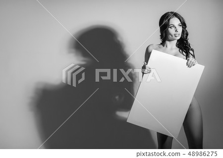 Sexy naked brunette woman holding empty board Sexy naked brunette woman holding empty board 48986275