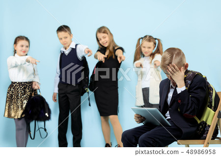 Little boy sitting alone on chair and suffering an act of bullying. Little boy sitting alone on chair and suffering an act of bullying. 48986958