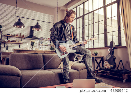 Participant of rock band having rehearsal in the living room 48989442
