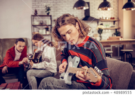Student with bob cut feeling inspired playing the guitar Student with bob cut feeling inspired playing the guitar 48989555