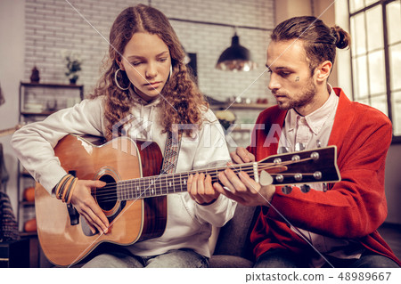 Teenage girl feeling excited while playing guitar for the first time 48989667