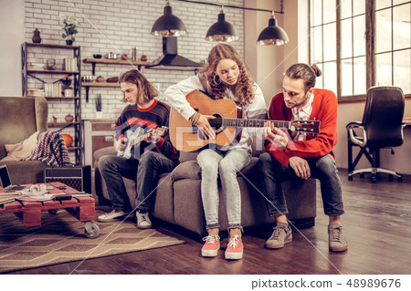 Caring boyfriend helping his beautiful girl playing the guitar 48989676