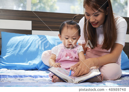 Mother and daughter reading together Mother and daughter reading together 48989748