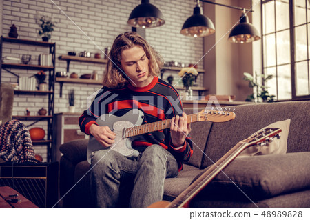 Student wearing jeans playing guitar and composing melody 48989828