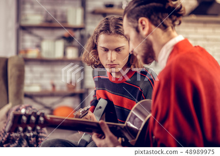 Handsome blonde-haired man playing guitar with brother 48989975