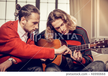 Bearded guitar tutor feeling busy teaching his talented student 48990668