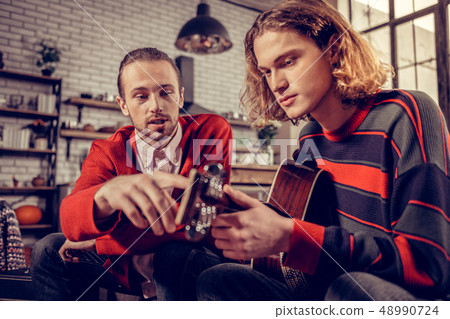 Bearded man explaining his friend some things about guitar 48990724