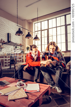Young man wearing red cardigan teaching his friend playing the guitar 48990725