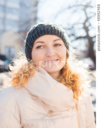 Smiling girl in a white clohtes looking at camera. Young woman winter portrait Smiling girl in a white clohtes looking at camera. Young woman winter portrait 48992468