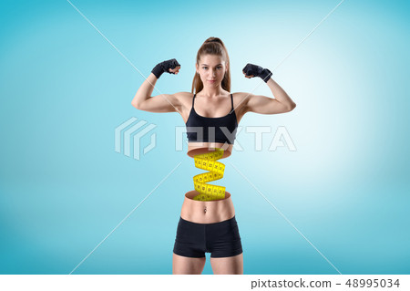 Young fit woman in short black gym top and shorts, in double bicep pose, upper body cut at waist and 48995034